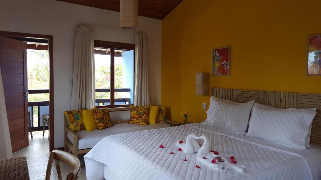 a bedroom with a white bed with a yellow wall at Pousada Paraíso do Forte in Praia do Forte