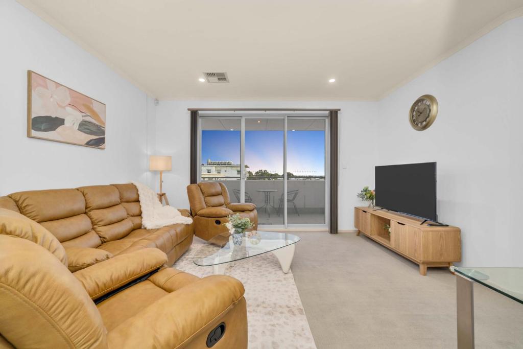 a living room with a couch and a tv at Modern Metro by Host Solutions in Mawson Lakes