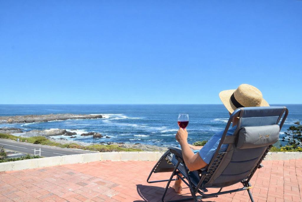 a person sitting in a chair with a glass of wine at 61 Lutie Katz in Yzerfontein