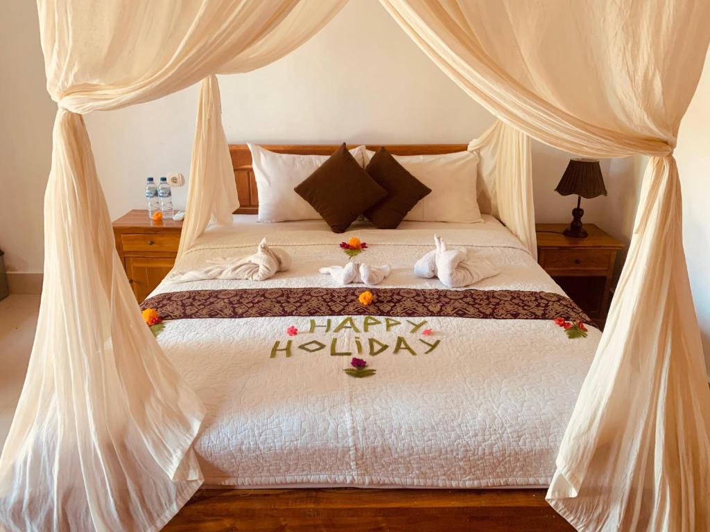 a bedroom with a bed with a happy holidays sign on it at Dika Homestay in Sidemen
