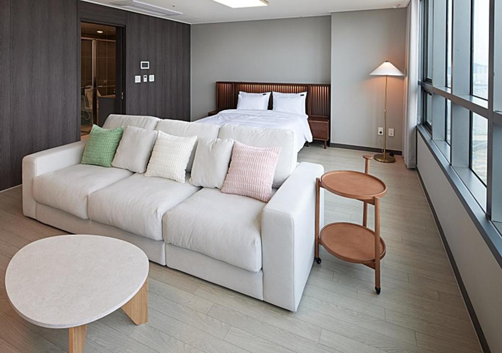 a living room with a white couch and a bed at Incheon Songdo Stay31 in Incheon