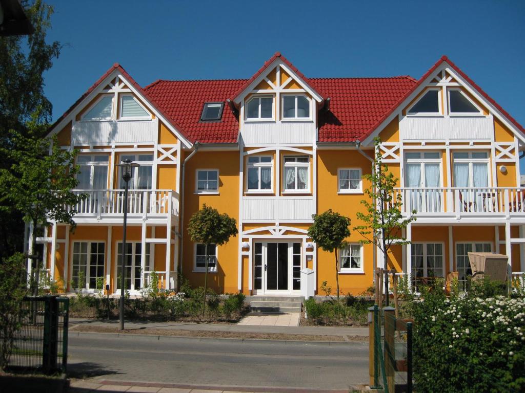 a yellow and white house with red roof at Uns Strandhus in Kühlungsborn