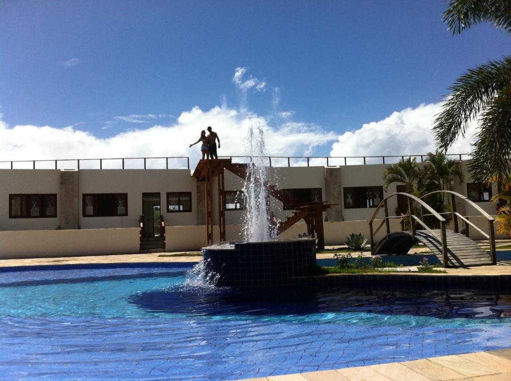 un hombre de pie en la parte superior de una fuente junto a una piscina en Apto em Condomínio Brisas do Amor, en Pipa
