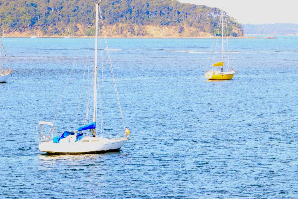 three sailboats floating in a large body of water at Sable Shores in Batemans Bay