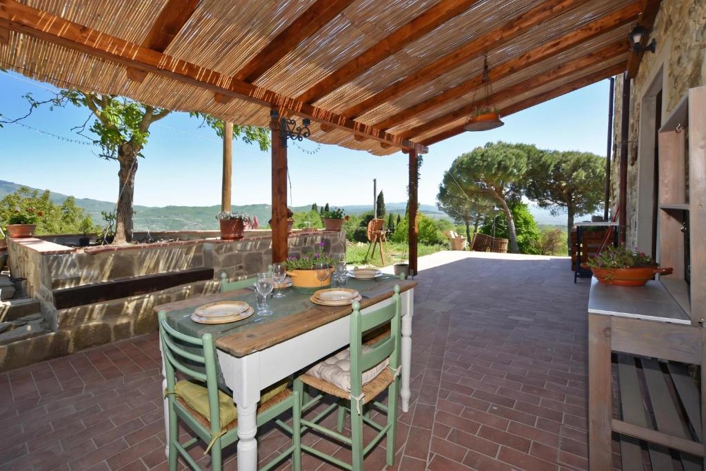 a patio with a table and chairs under a wooden pergola at Dimora Belfiore - Happy Rentals in Capolona