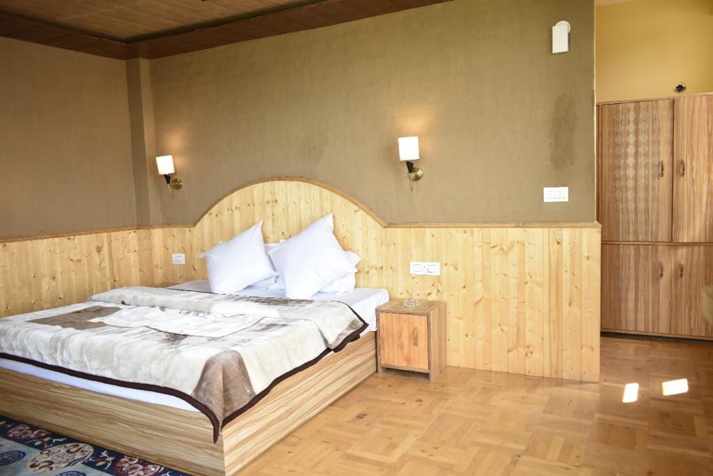 a bedroom with a large bed with a wooden headboard at Casa De Barro in Jagatsukh