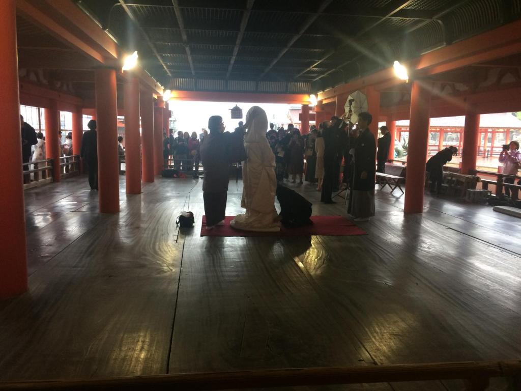 une mariée et un marié assis sur le sol d'un bâtiment dans l'établissement Wholeearth Ryokan Hiroshima, à Hiroshima