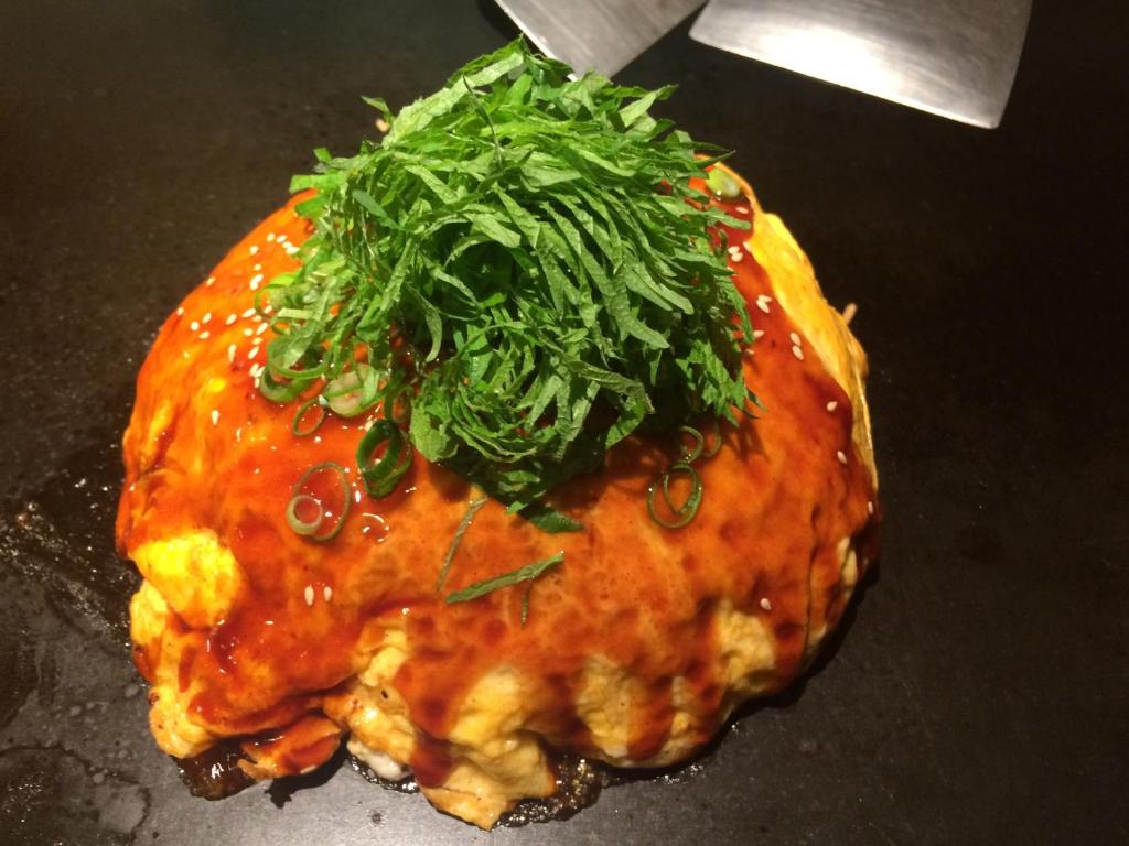 un morceau de nourriture avec des légumes verts dessus dans l'établissement Wholeearth Ryokan Hiroshima, à Hiroshima