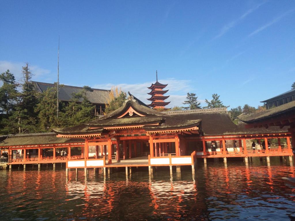 un bâtiment asiatique sur l'eau avec une tour dans l'établissement Wholeearth Ryokan Hiroshima, à Hiroshima