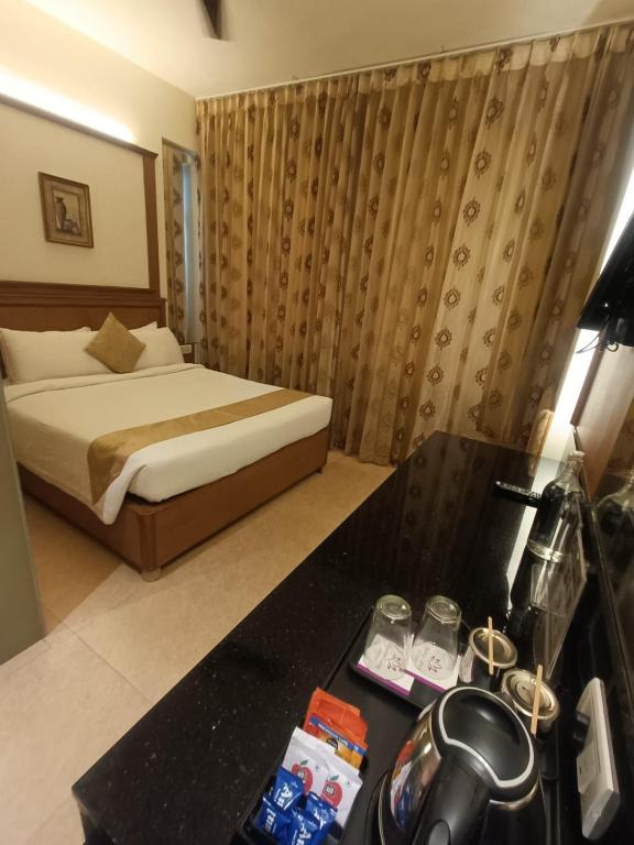 a hotel room with a bed and a desk with a phone at Hotel Roopa in Mysore