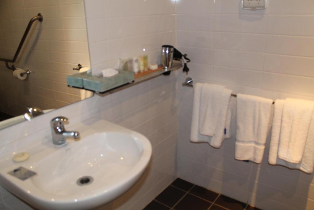 a bathroom with a white sink and a white towel rack at Hunter Gateway Motel in Maitland