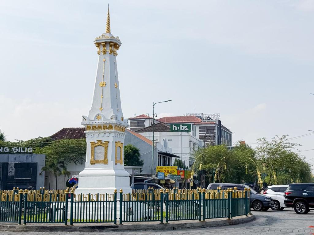 a white monument with a clock on it next to a fence at HUBS Hostel Yogyakarta in Yogyakarta