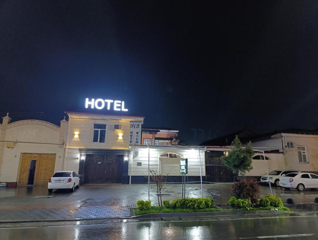 a hotel with cars parked in a parking lot at night at Bilol Guest House in Samarkand