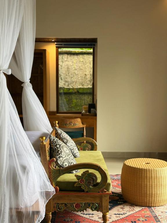 a bedroom with a bed and a chair and a window at Lira House by Yukaya Escape in Tegalalang