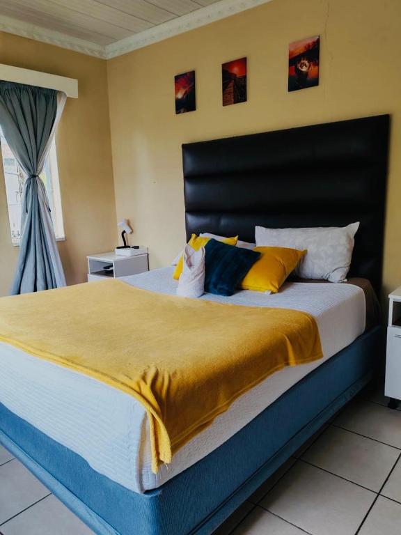 a bedroom with a large bed with yellow and blue pillows at Monono Guesthouse in Bloemfontein