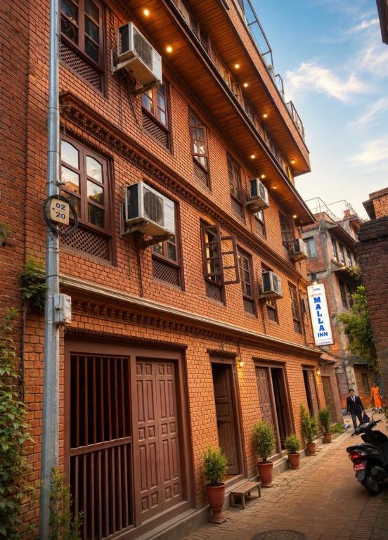 a red brick building with windows on a street at Hotel Malla Inn in Bhaktapur