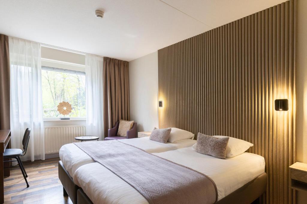 a hotel room with a large bed and a window at 50|50 Hotel Belmont in Ede