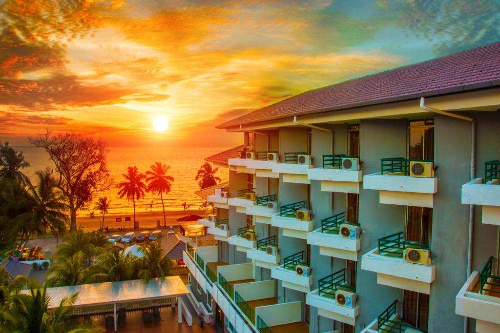 uma vista de um hotel com o pôr-do-sol ao fundo em Akar Beach Resort em Porto Dickson