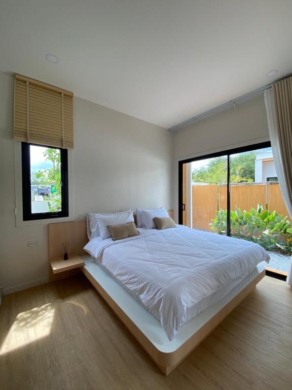 a bedroom with a large white bed with windows at The Town Pool Villas in Krabi