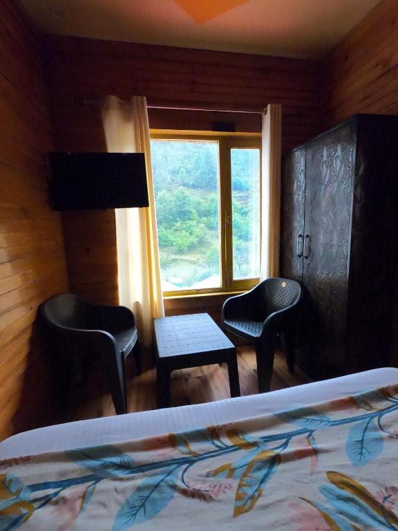 a bedroom with a bed and chairs and a window at Bagwan Kainchi Stay in Bhowāli