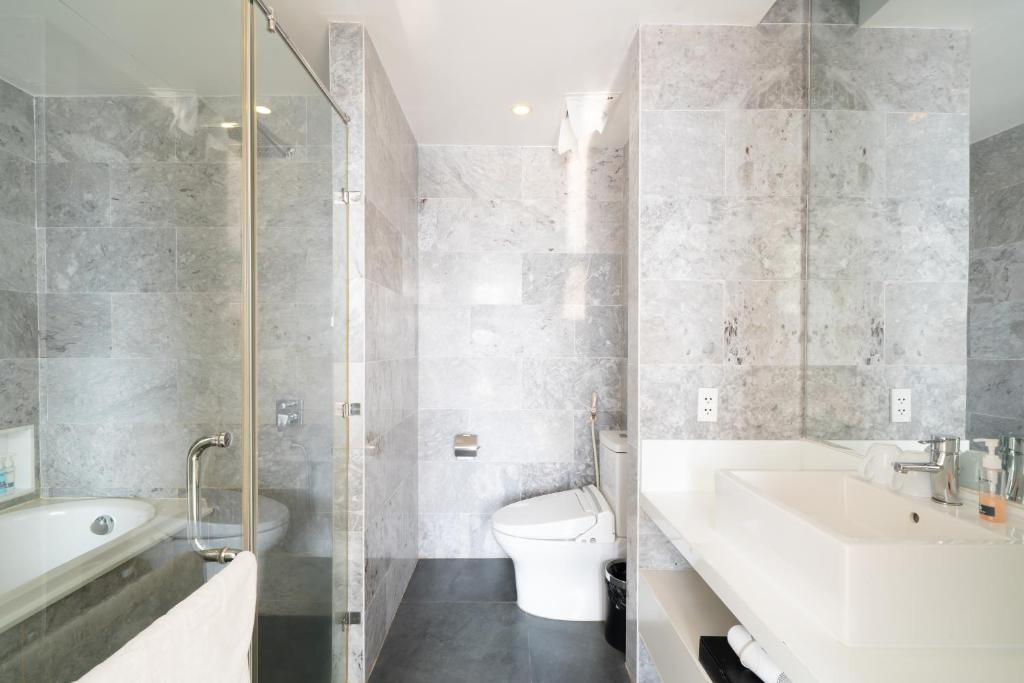 A marble-look bathroom with a bathtub, enclosed shower, toilet, and broad vanity.