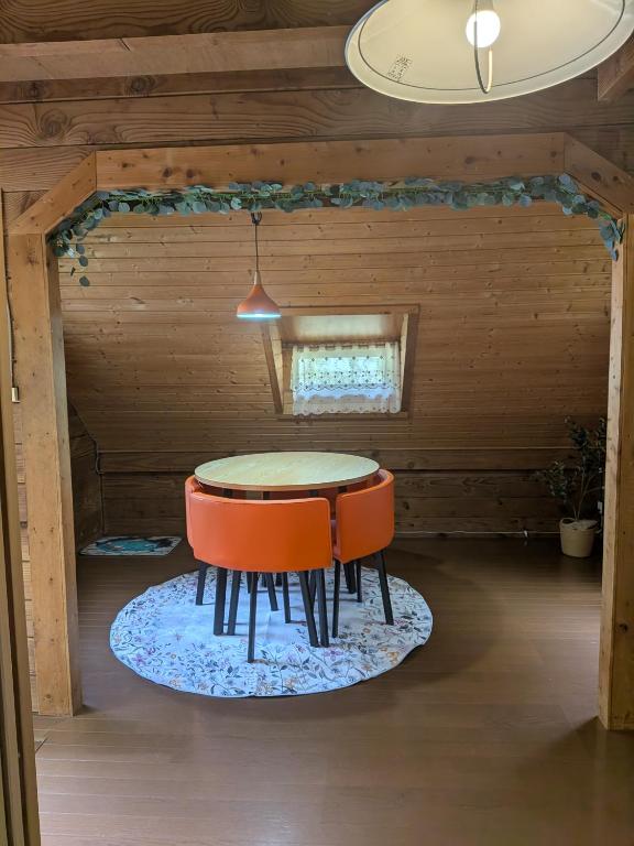 a dining room with a table and two orange chairs at のんびれっじ つくし棟 in Anazawa