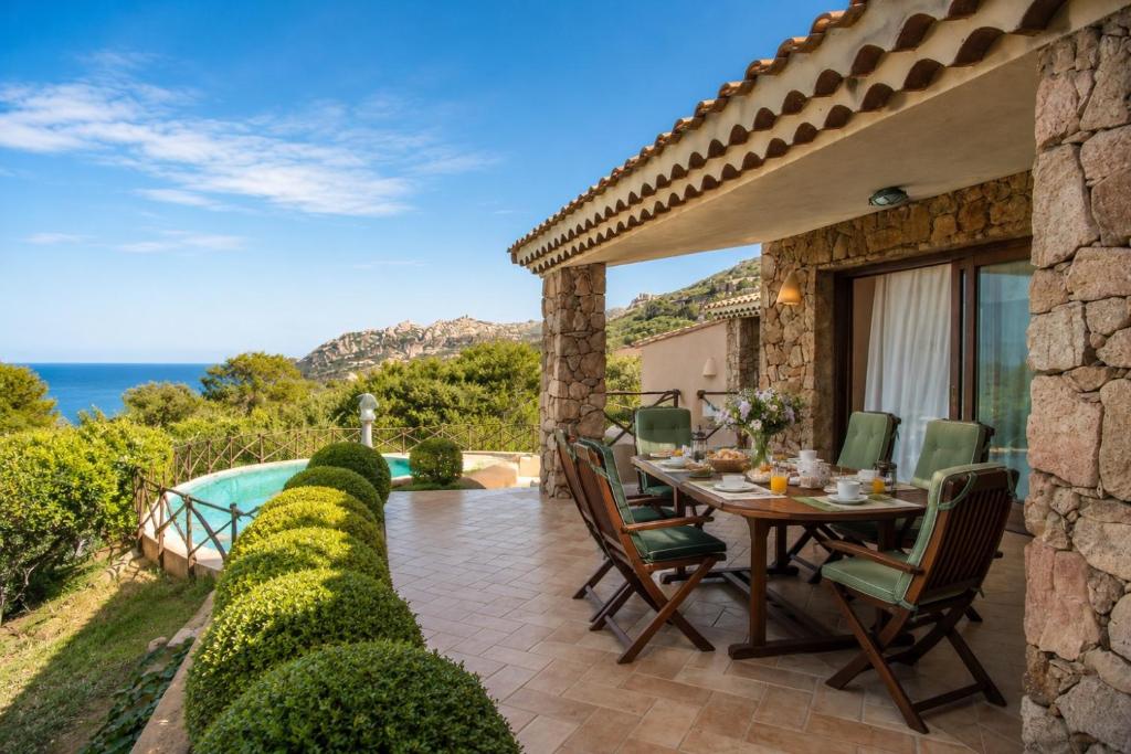 a patio with a table and chairs and a view of the ocean at Villa Turchese - Key to Villas in Costa Paradiso