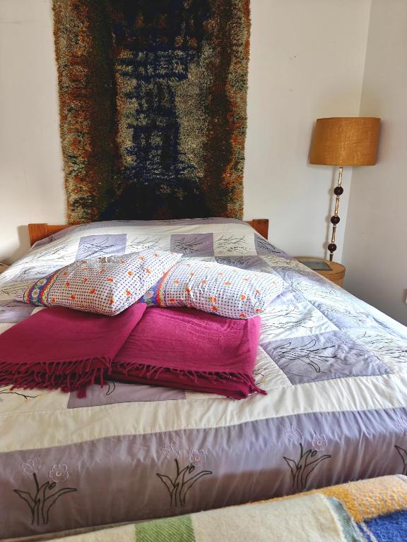 a bed with pillows on it with a painting on the wall at Päivärannantila in Pihtipudas