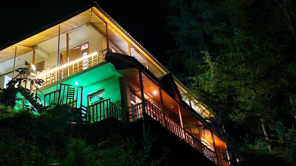 a house with green lights on the side of it at Ananta Valley Home's in Kulu