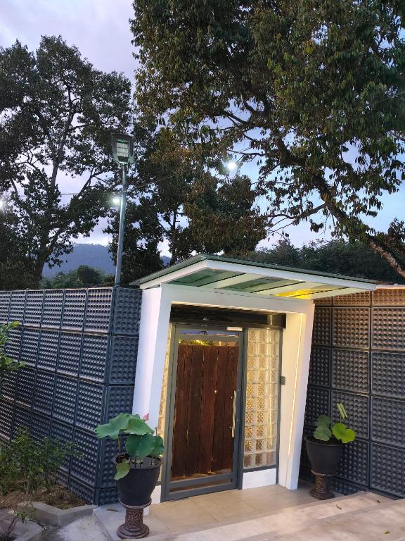 a small house with a brown door and a fence at 19 Farmstay in Bukit Mertajam