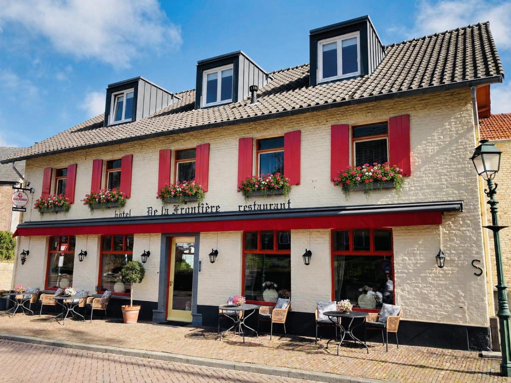 a building with red shutters on a street at De La Frontière Bed & Borrelbistro in Slenaken