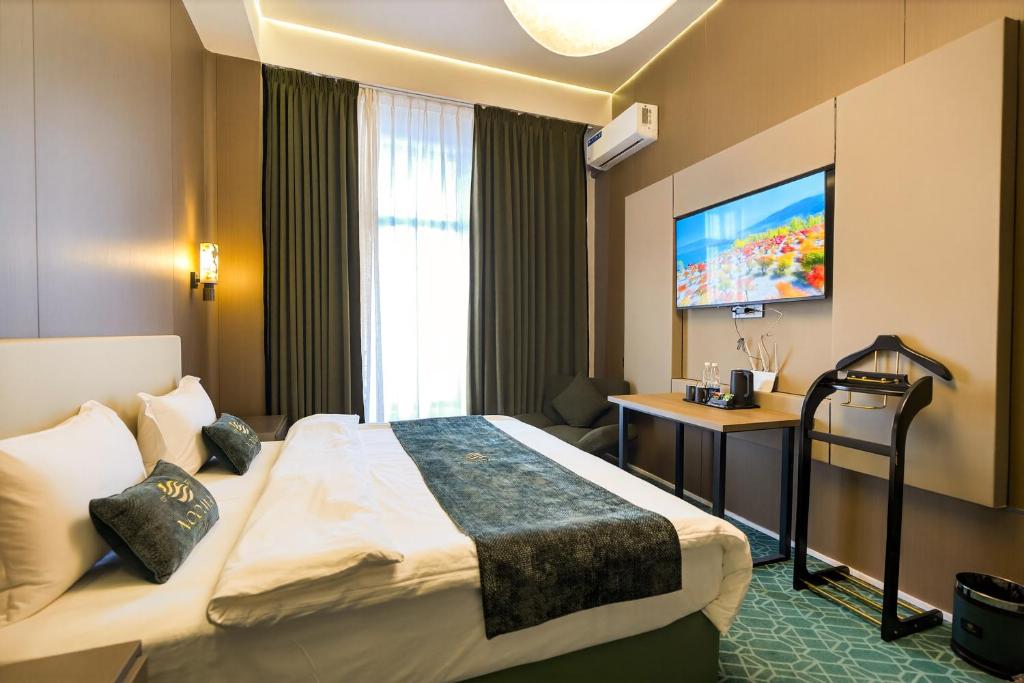 a hotel room with a bed and a flat screen tv at NOOMA Hotel Aitmatova in Bishkek