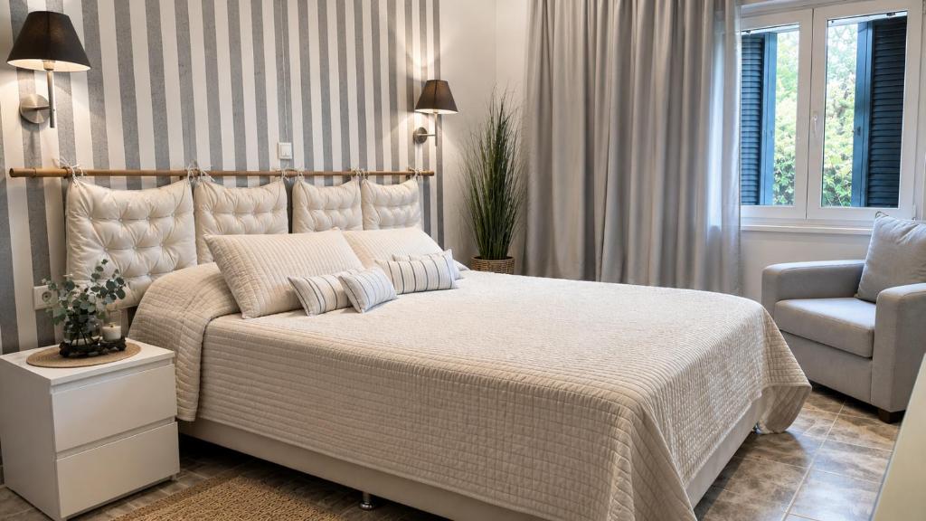 a bedroom with a large bed and a chair at Kaloudis Studios & Apartments in Dassia