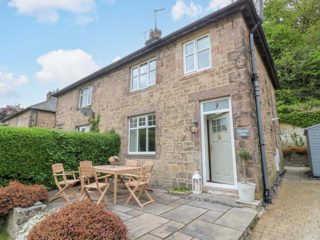 a brick cottage with a table and chairs in front of it at Lumford Mill Cottage in Bakewell