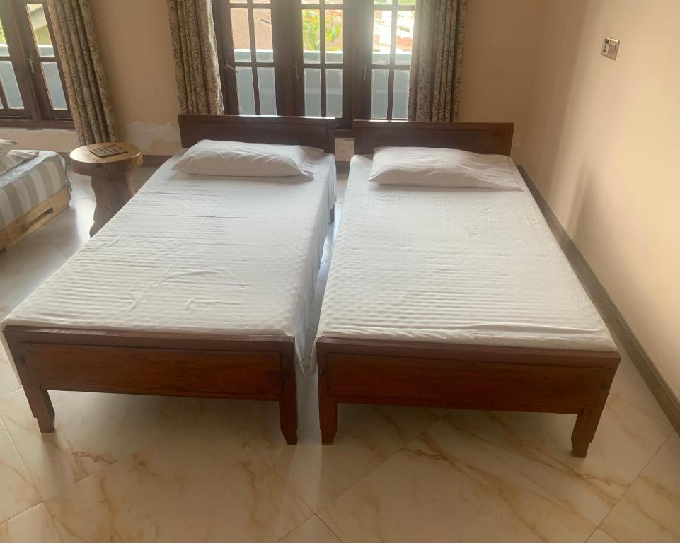 two beds are sitting in a room with at Neem Homestay in Hatton