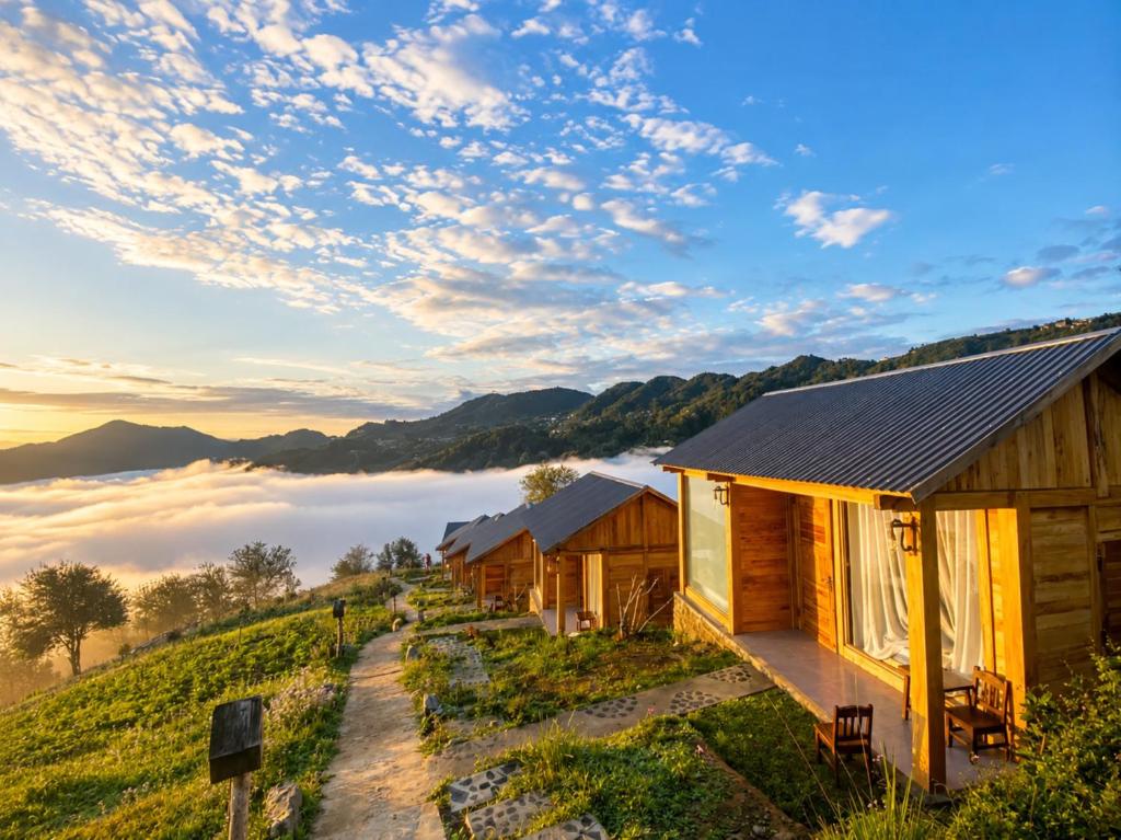 a row of wooden cabins on a hill with a foggy valley at Samu Retreat Tà Xùa in Bắc Yên
