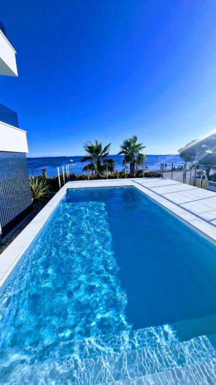 a large blue swimming pool with a view of the ocean at Dinary Deluxe Apartments in Vir