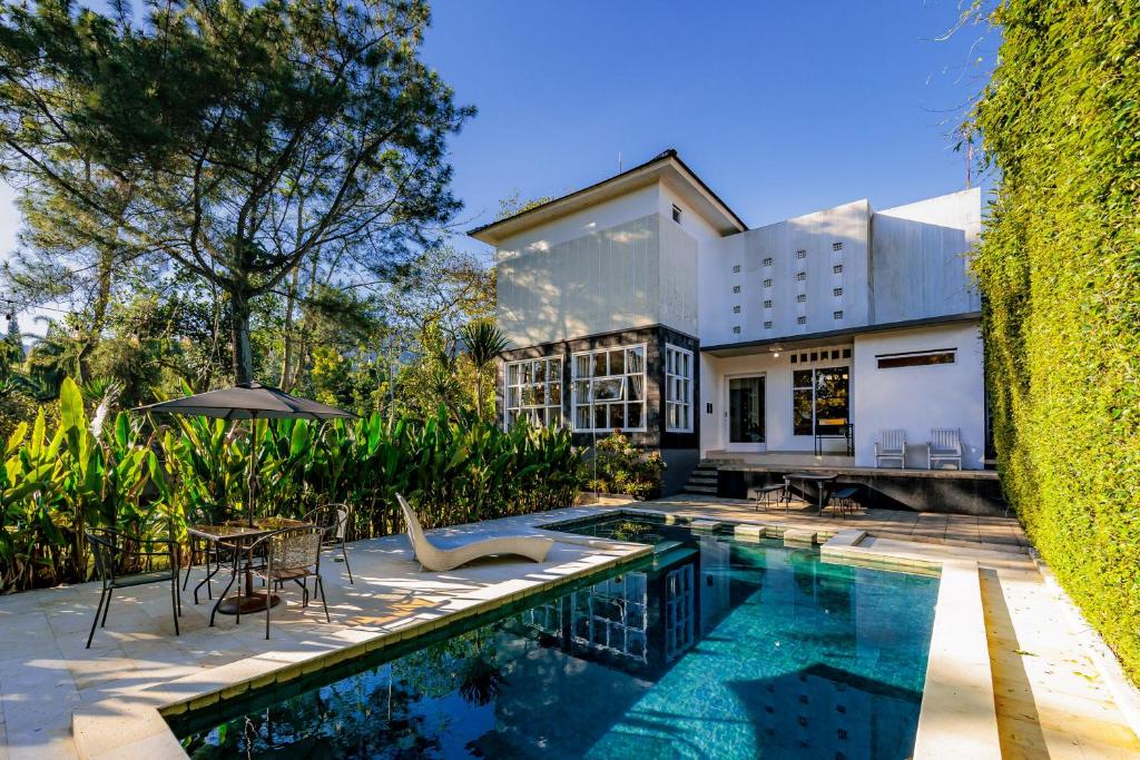a house with a swimming pool next to a building at The Lavana Signature Villa Herrera Puncak in Puncak