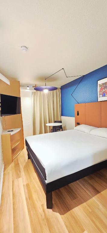 a bedroom with a large bed and a desk at ibis Lyon Est Bron in Bron