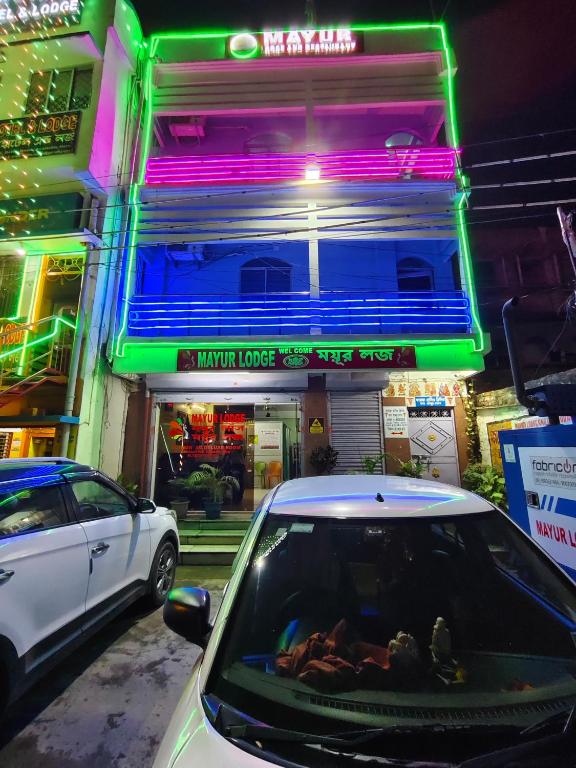 a car parked in front of a building with neon lights at Mayur Lodge And Restaurant in Khejuria Ghāt