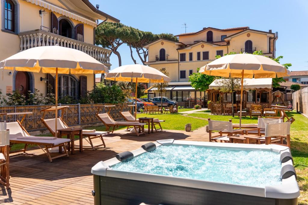 a hot tub with tables and chairs and umbrellas at Hotel Virginia in Marina di Massa