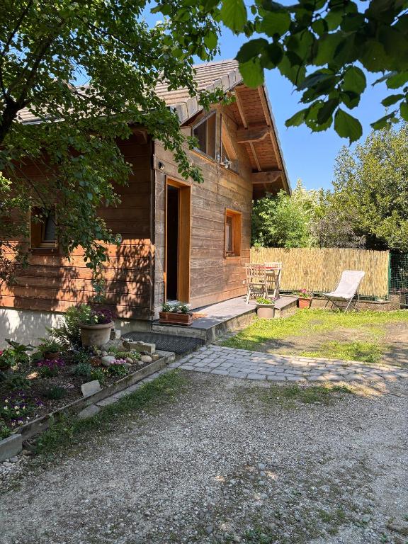 a wooden house with a bench in the yard at Omazot au calme dans verdure in Aix-les-Bains