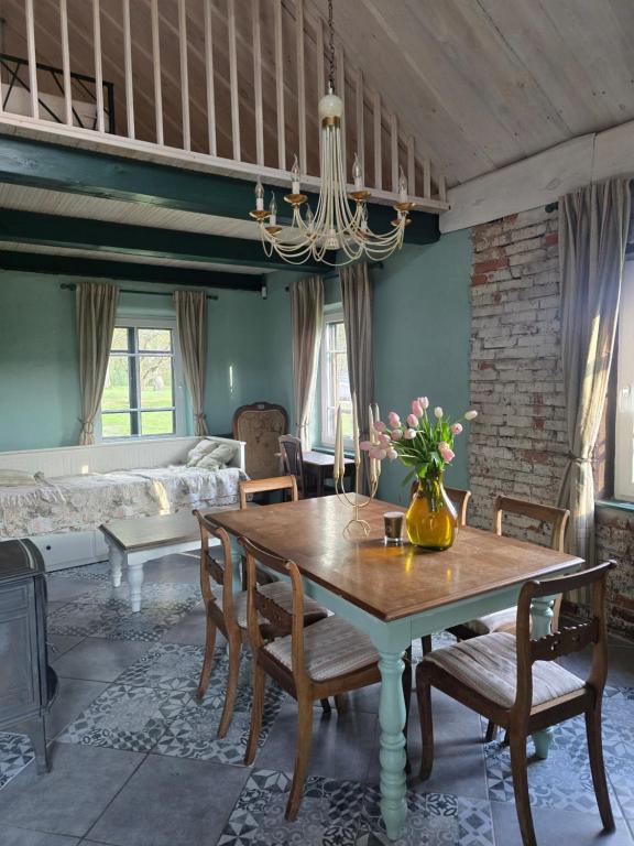 a dining room with a table and a bed at Žemosios Panemunės dvaro sodininko namas in Žemoji Panemunė