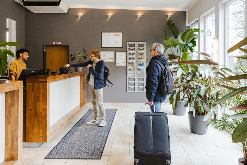 a man and a woman standing at a counter with a suitcase at Hostel SLEPS in Augsburg