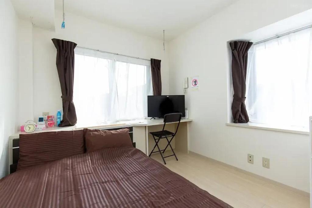 a bedroom with a bed and a desk with a television at アセット北初富 - 長期滞在歓迎 キッチン付きで一人旅やビジネス出張におすすめ 成田空港へ直通 in Kamagaya