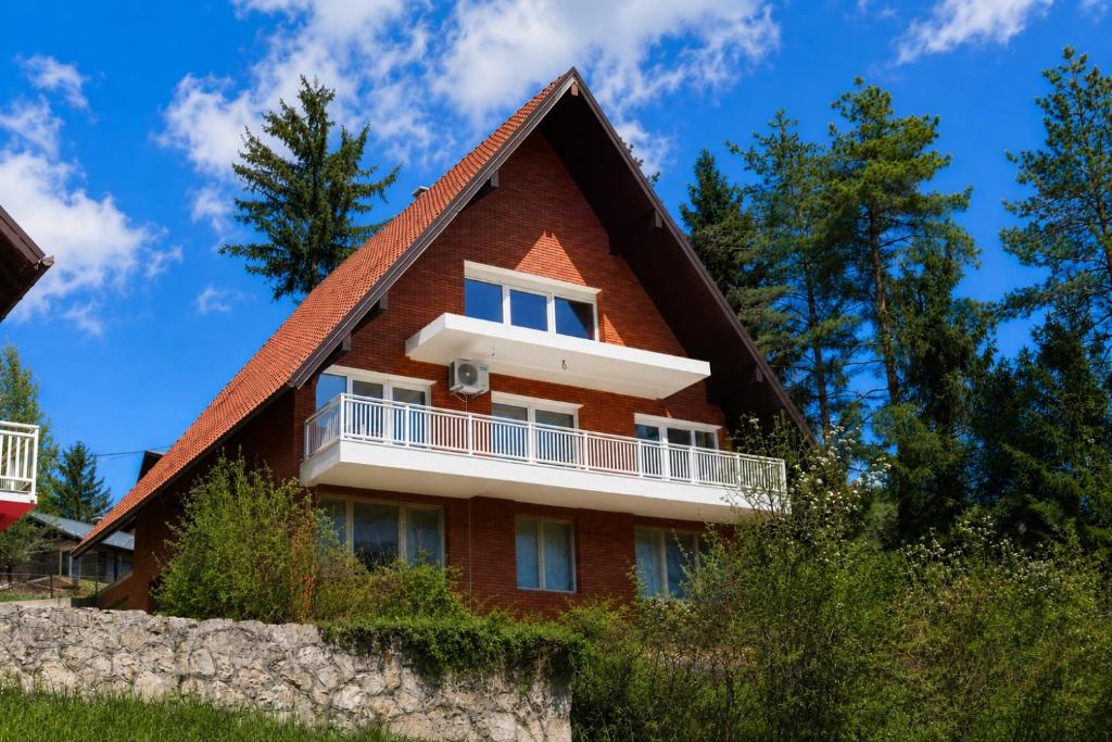 a red house with a white balcony and trees at Apartment Baki in Jajce