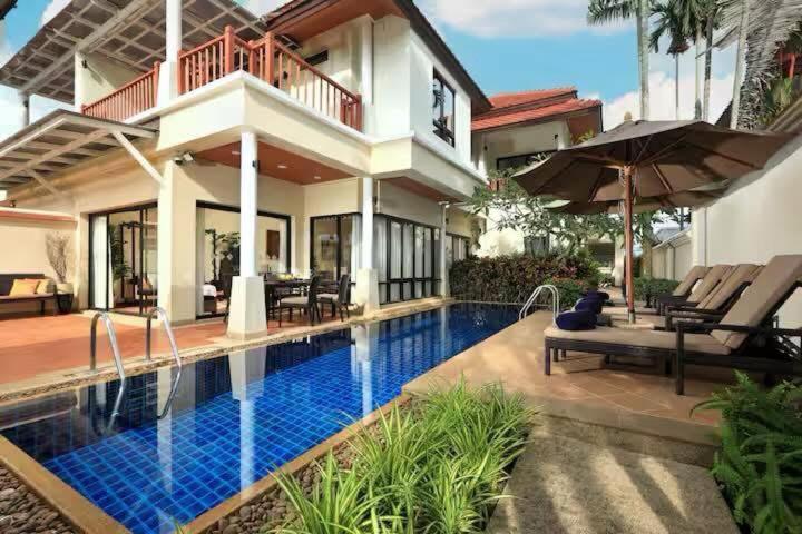 a villa with a swimming pool in front of a house at Laguna Fairway 3B villa-golf view in Laguna Phuket
