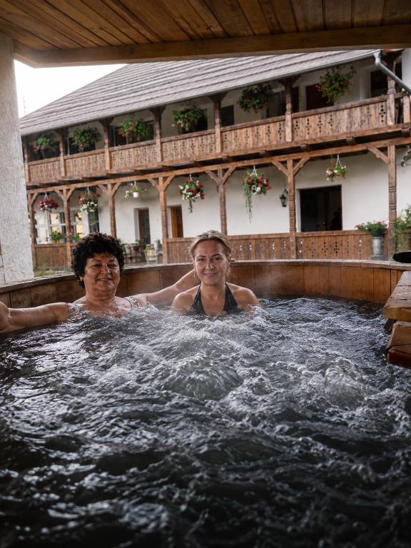 two men are sitting in a hot tub at Conacul Birtoc Refugiu Tradițional în Maramureș in Văleni
