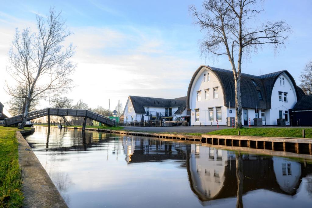 a building next to a river with buildings at Hotel Giethoorn in Giethoorn