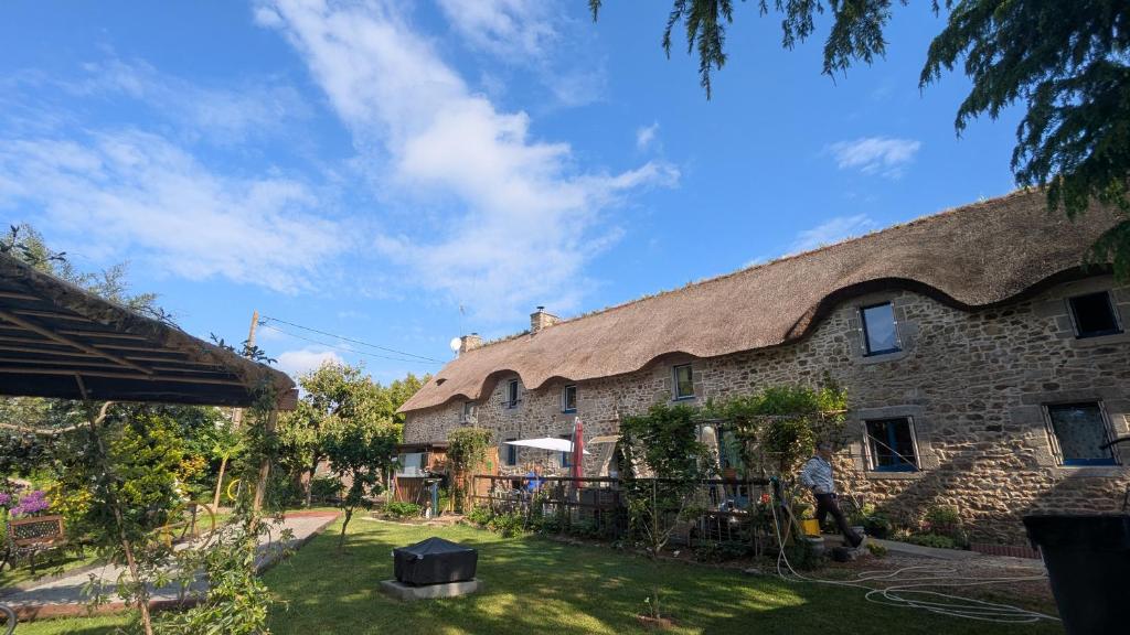 a large stone house with a thatched roof at La Chaumière en Bellevue in Muzillac
